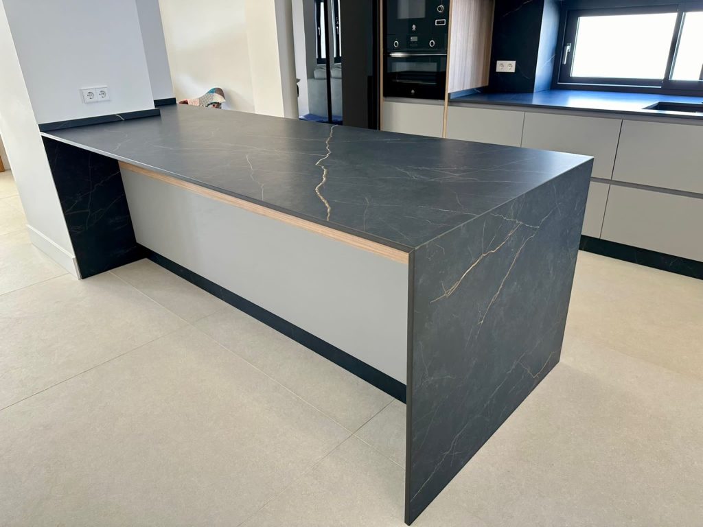 Detalle constructivo de isla en Dekton negro con puerta gris mate y madera nogal
