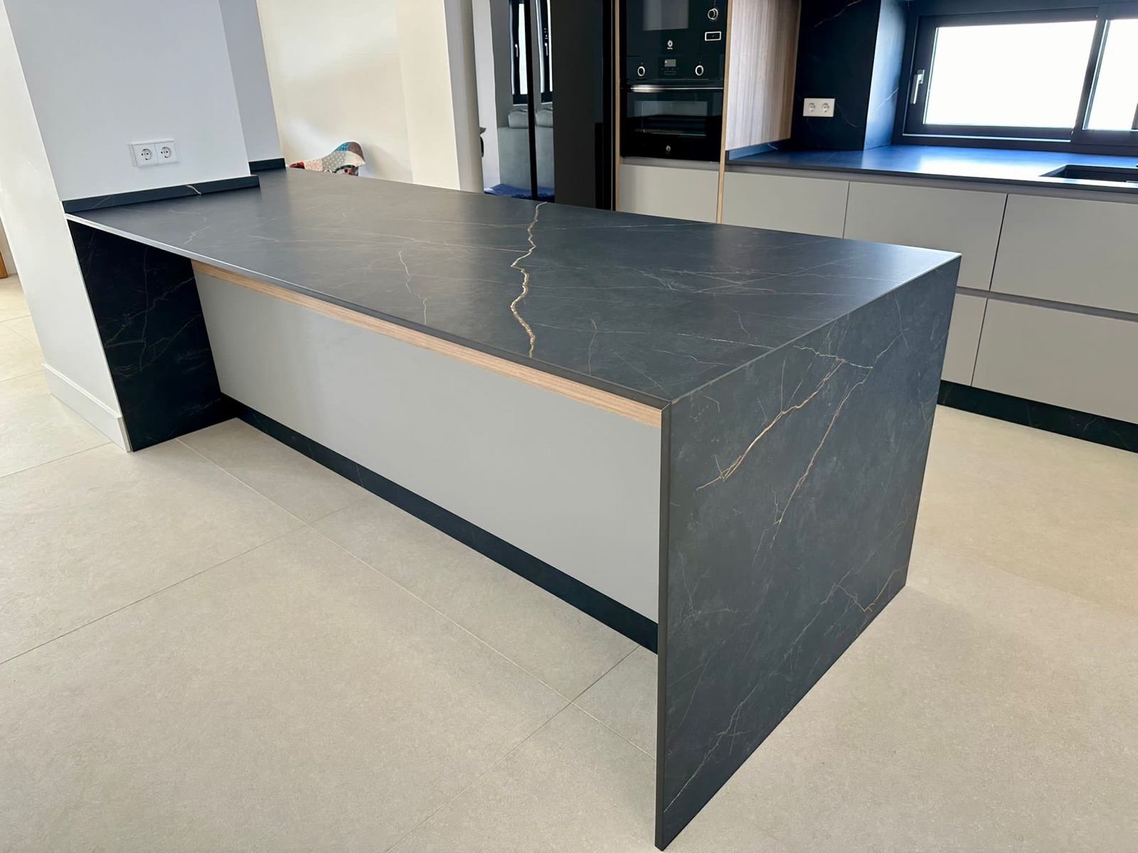 Detalle isla Dekton negro veteado dorado con puerta gris