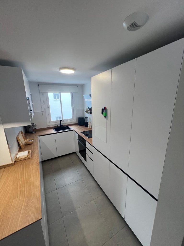 Cocina moderna con frentes en beige lino, isla americana blanca y frigorífico americano inox