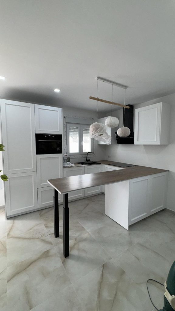 Cocina estilo shaker en blanco con península de encimera de madera y campana negra angular