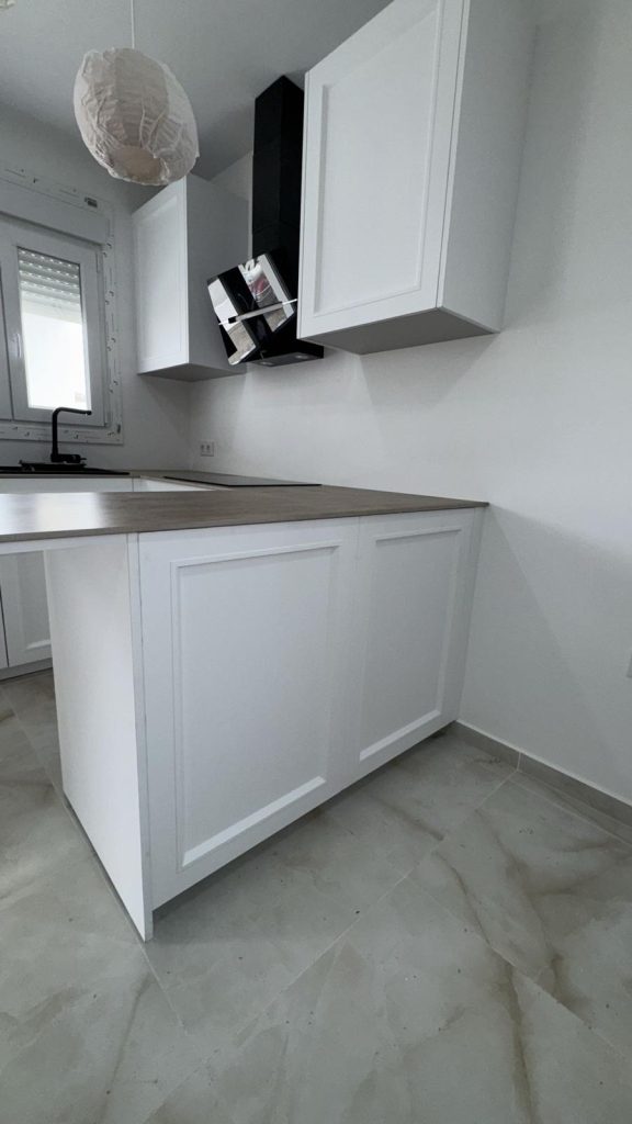 Detalle de la península con encimera madera y campana angular en cocina clásica shaker