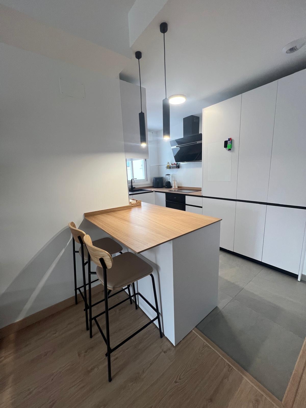 Cocina blanca minimal con barra de madera