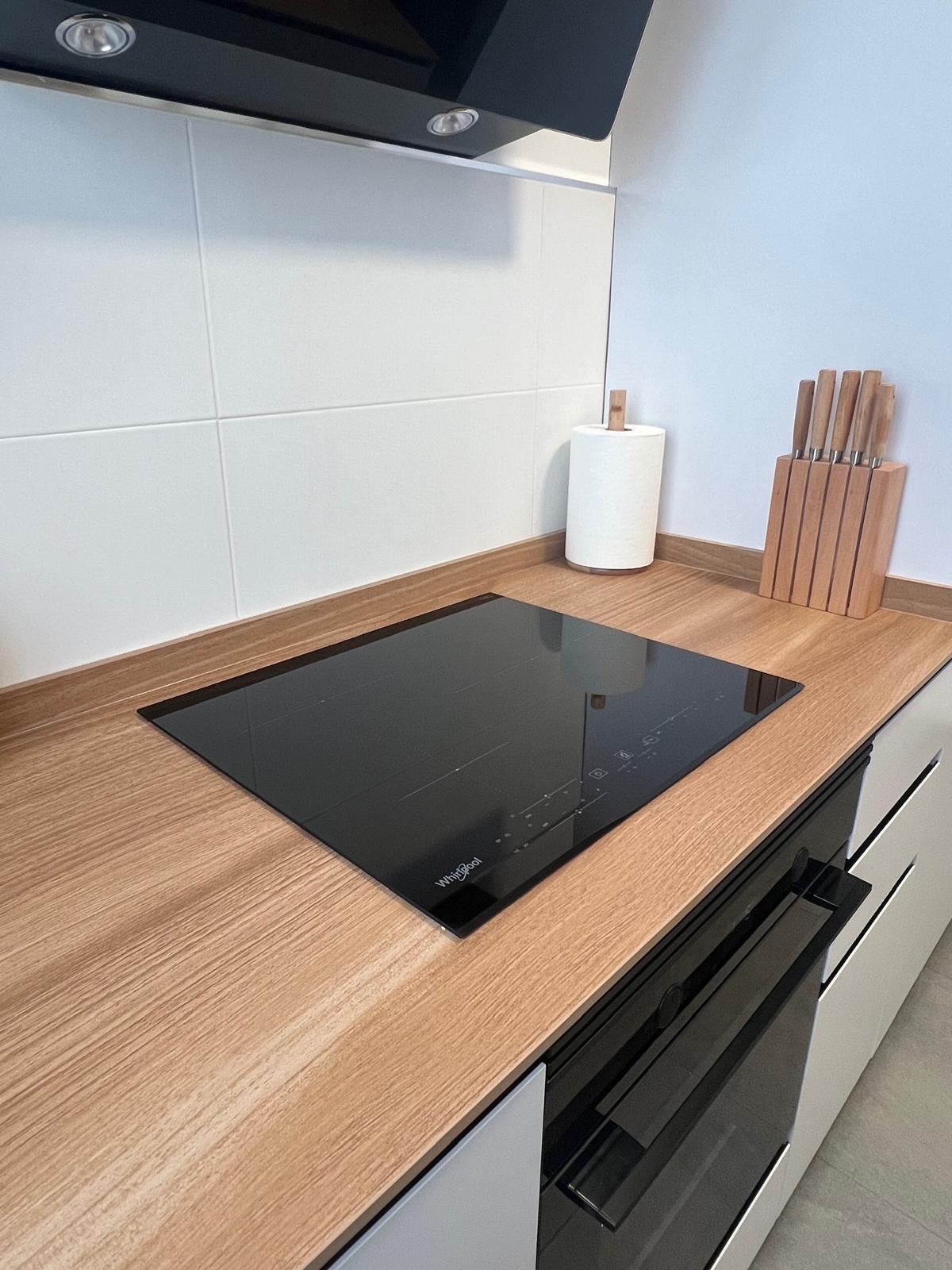 Cocina blanca con barra de madera y taburetes