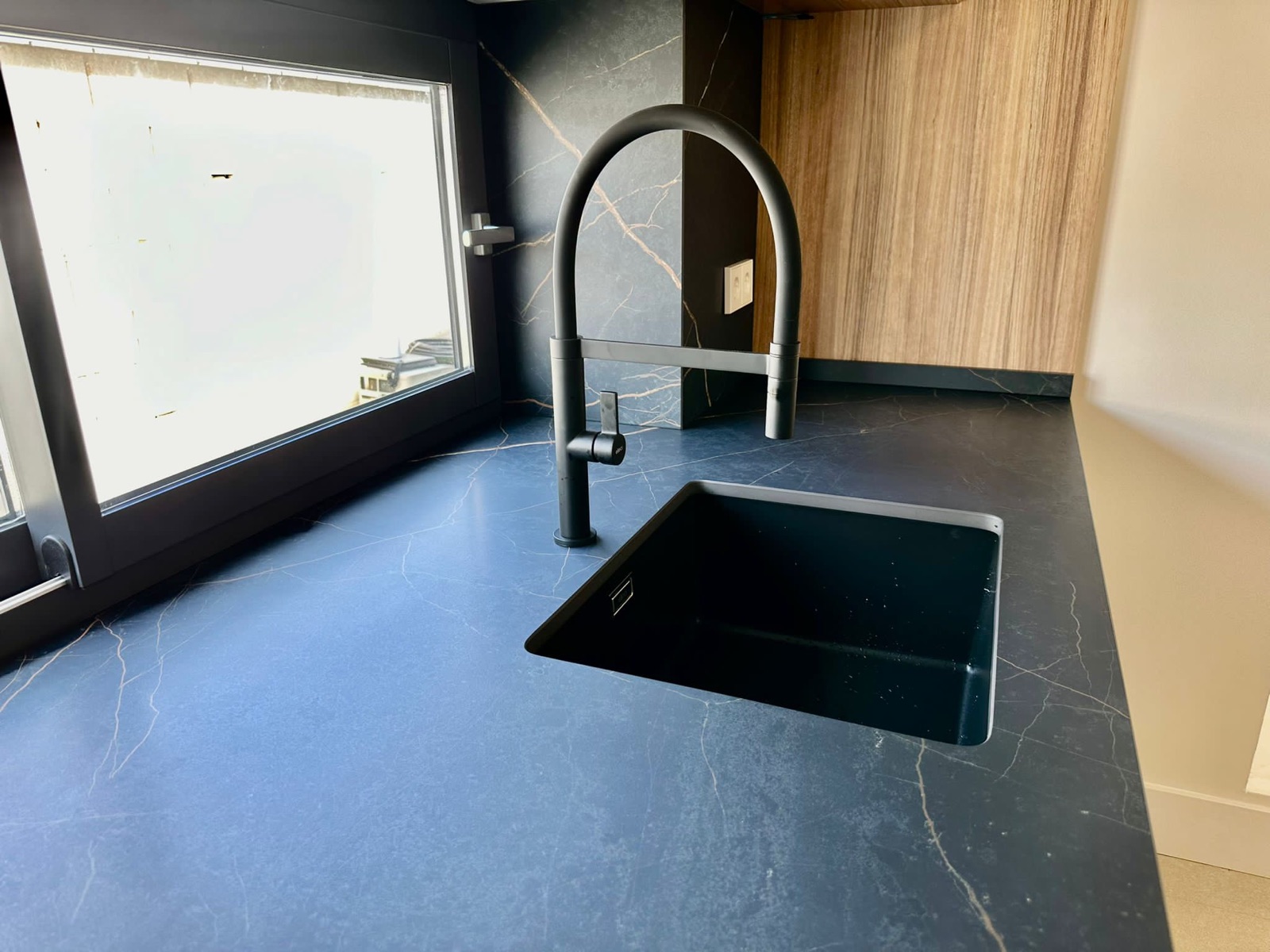 Detalle grifería y fregadero negros sobre Dekton