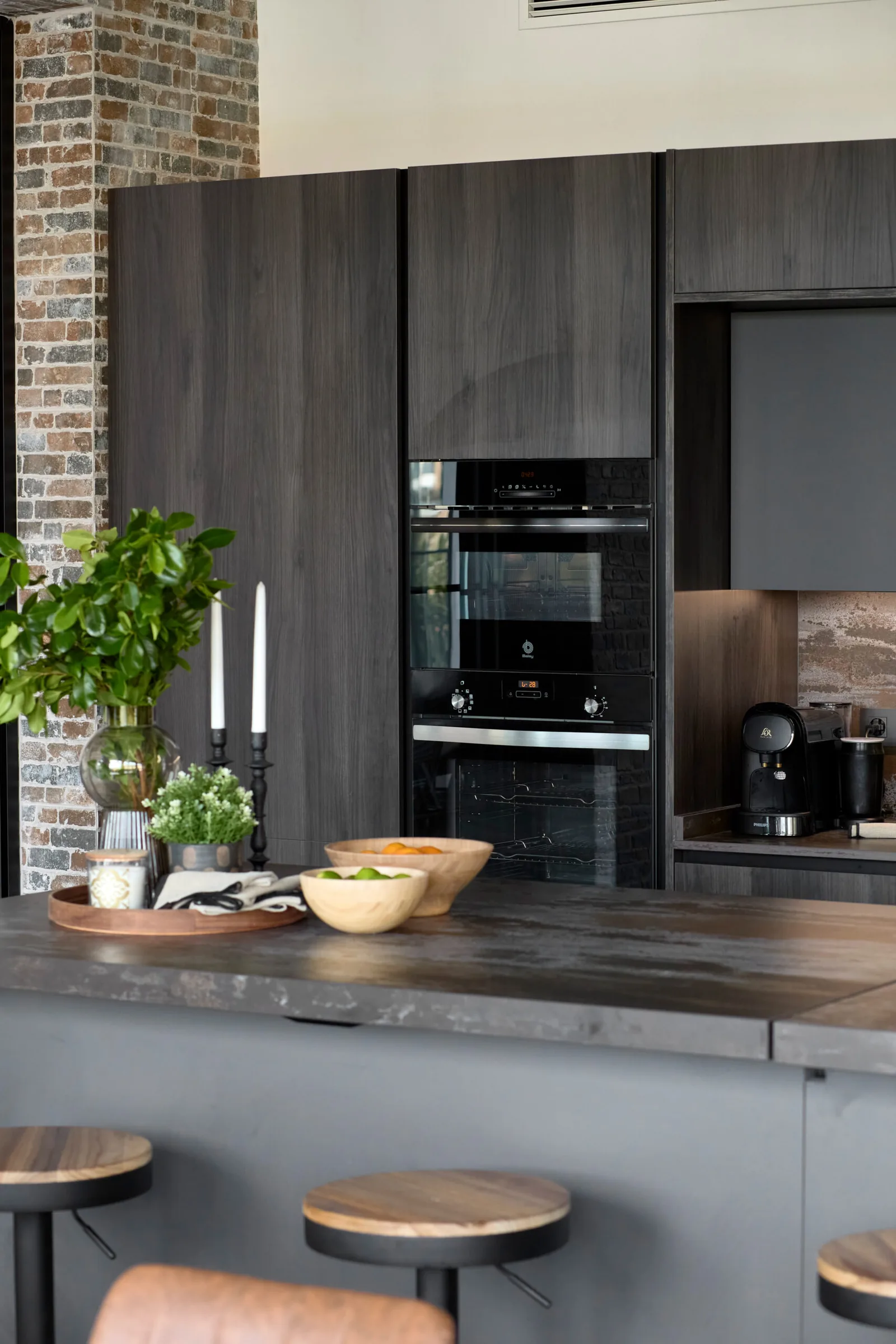 Con isla central y estetica industrial en tonos oscuros — cocina a medida de Rosso Home Design en Chiclana