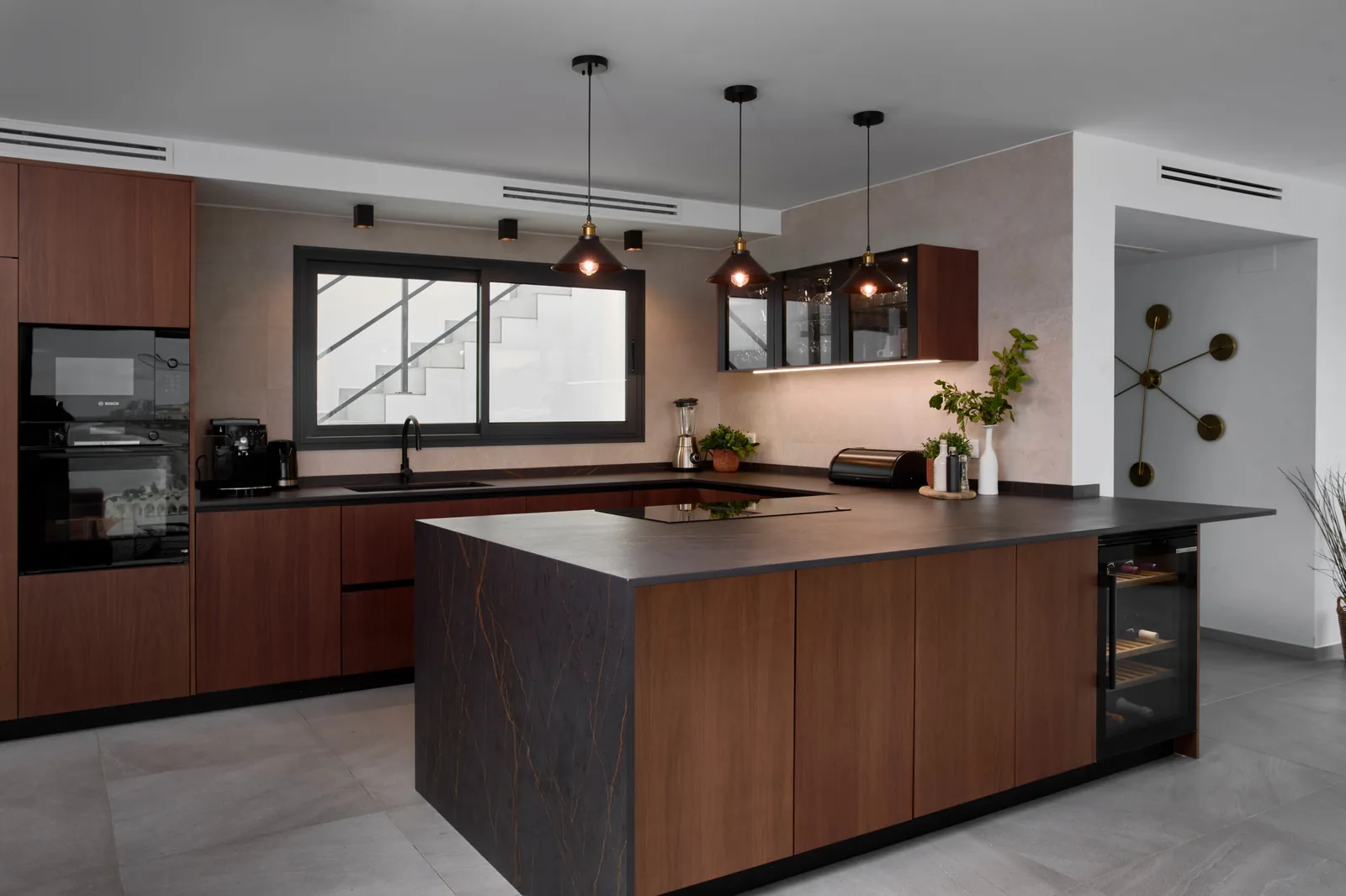 En u peninsula madera nogal — cocina a medida de Rosso Home Design en Jerez de la Frontera