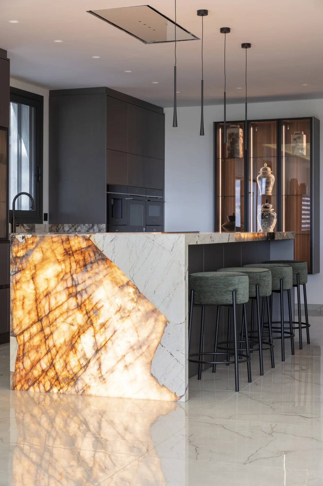 Cocina a medida con isla central en piedra natural retroiluminada — Rosso Home Design, Cádiz
