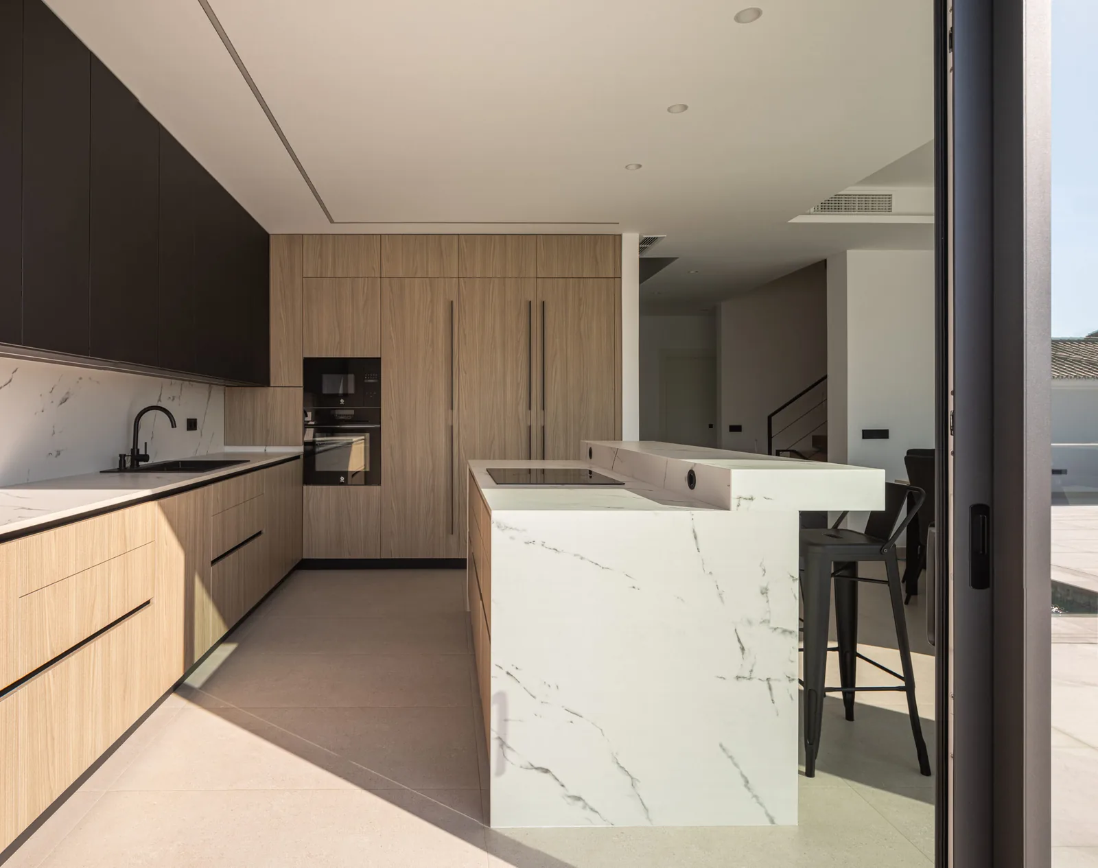 Moderna isla muebles hasta techo — cocina a medida de Rosso Home Design en Cádiz